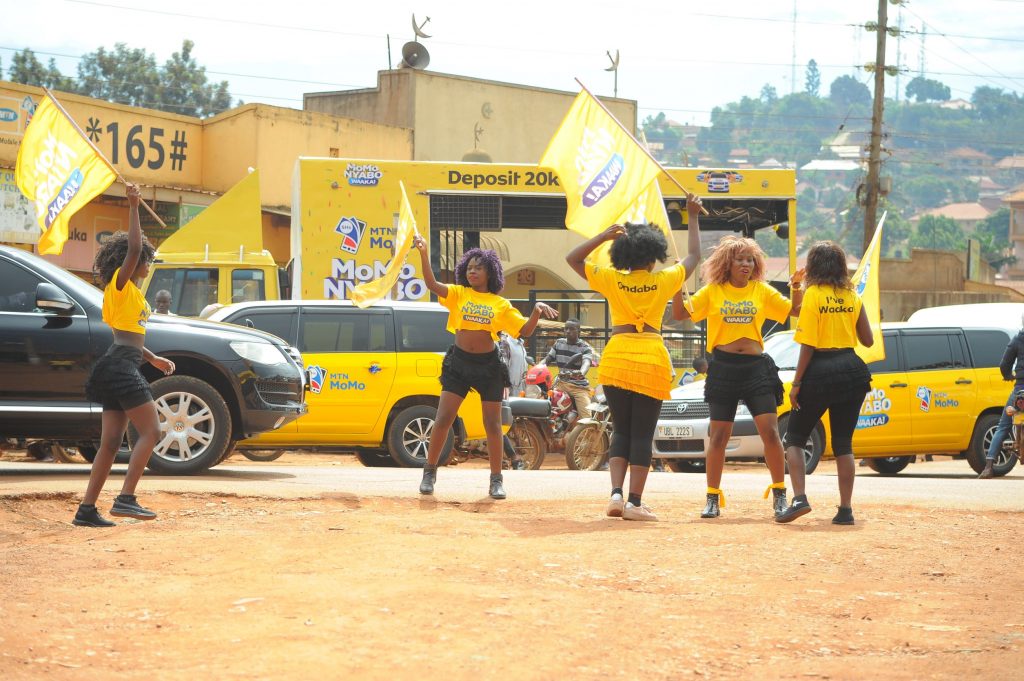 A group of beautiful ladies dance infront of a rig entertaining masses in Kampala during the MTN MoMo Nyabo Waaka Awareness drive yesterday