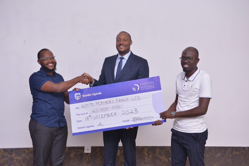 Robert Mukiza centre the Director General at Uganda Investment Authority handing over a dummy cheque to entrepreneurs of White Feathers Ranch Limited